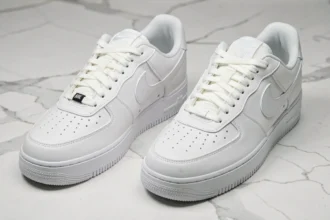 Comparaison côte à côte d'une Nike Air Force 1 authentique et d'une contrefaçon sur marbre blanc, révélant les différences de couture et de logo